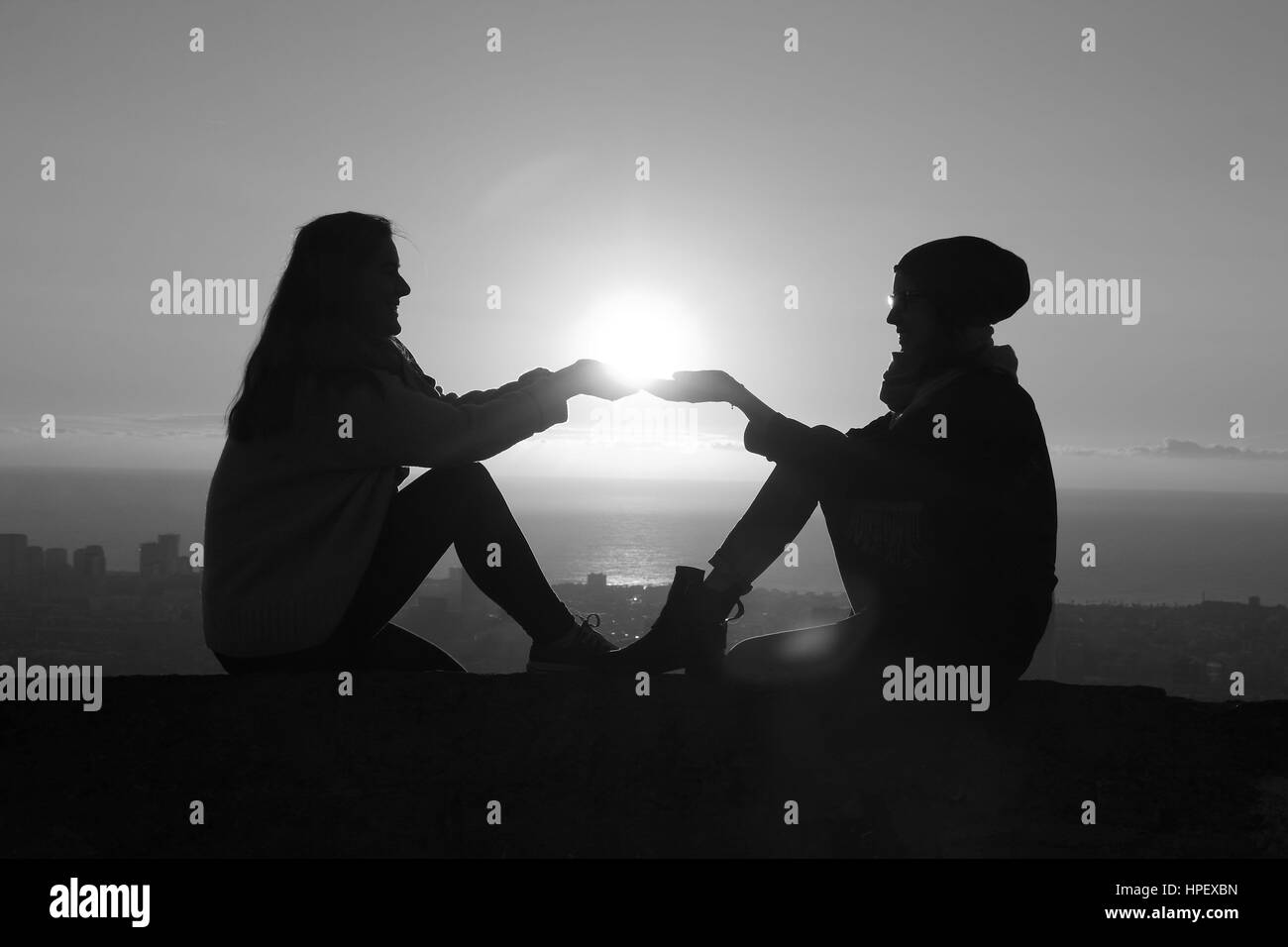 Zwei Frauen, die mit der aufgehenden Sonne in der Hand Stockfoto