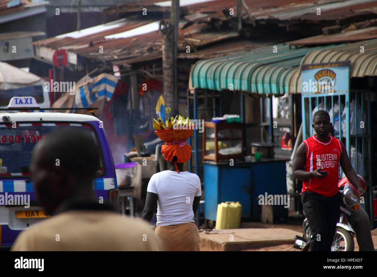 Einheimische Frau mit Korb mit Bananen auf dem Kopf in Entebbe Stockfoto