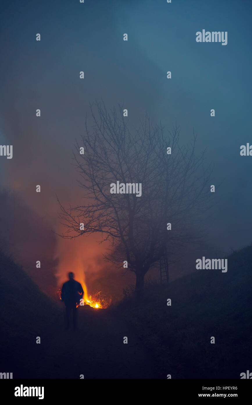 Mann in der Nacht auf der Flucht vor einem Feuer auf einem Berg Stockfoto