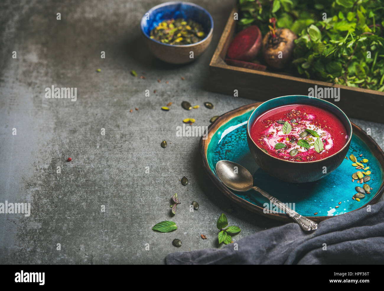 Frühling-Detox-rote Bete-Suppe mit Minze, Chia, Flachs und Kürbis Samen auf blaue Keramik-Platte über graue konkreten Hintergrund, Textfreiraum. Diäten, sauber Essen Stockfoto