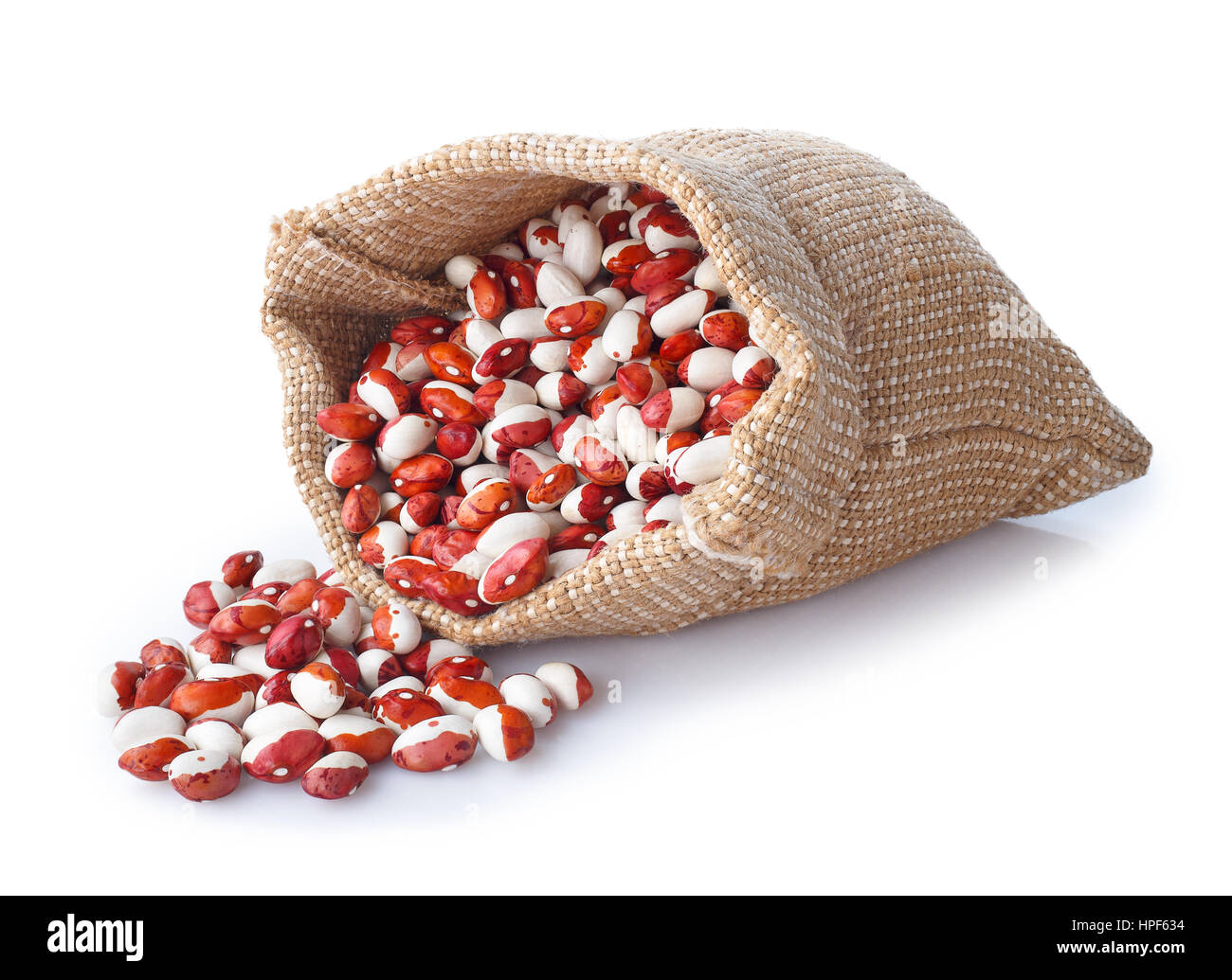 ungekocht verstreuten Kidney-Bohnen in Sackleinen Tasche isoliert auf weißem Hintergrund. Pinto-Bohnen Stockfoto