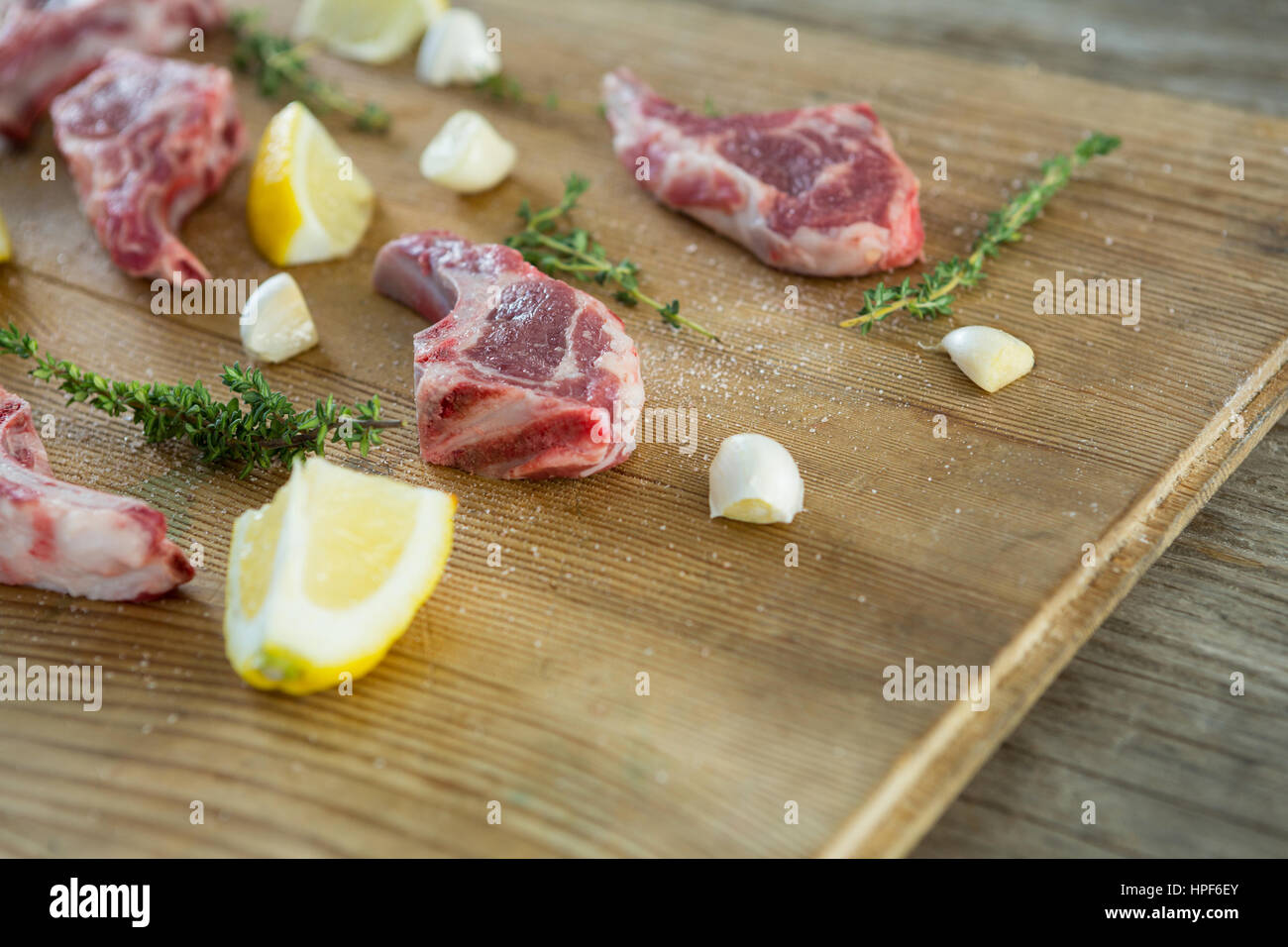 Roh-Koteletts, Kräuter und Zitrone aus Holz Hintergrund Stockfoto