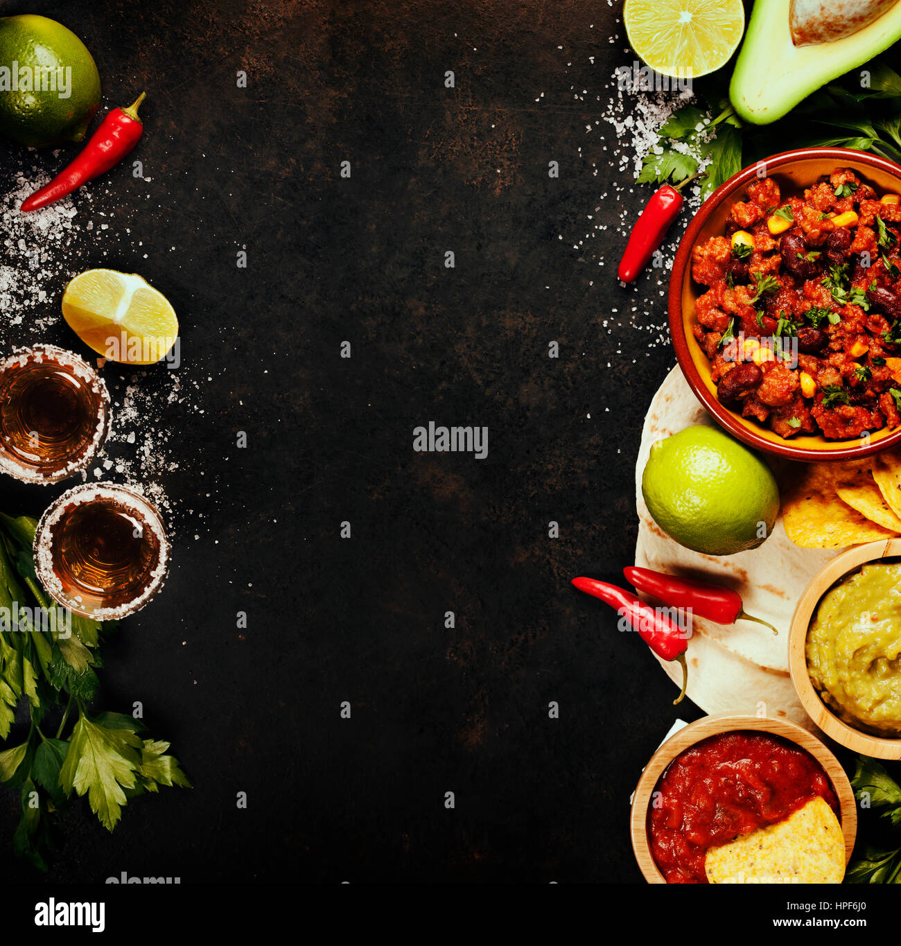 Mexikanisches Essenskonzept: Tortilla-Chips, Guacamole, Salsa, Chili mit Bohnen, Tequila Shots und frischen Zutaten über Vintage rostigen Metall-Hintergrund. An Stockfoto