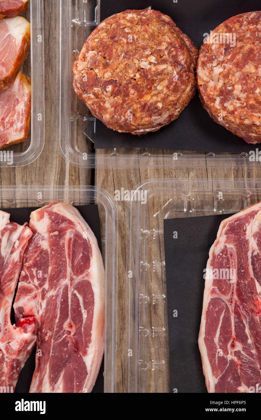 Sorten von Fleisch in Plastikboxen aus Holz Hintergrund Stockfoto