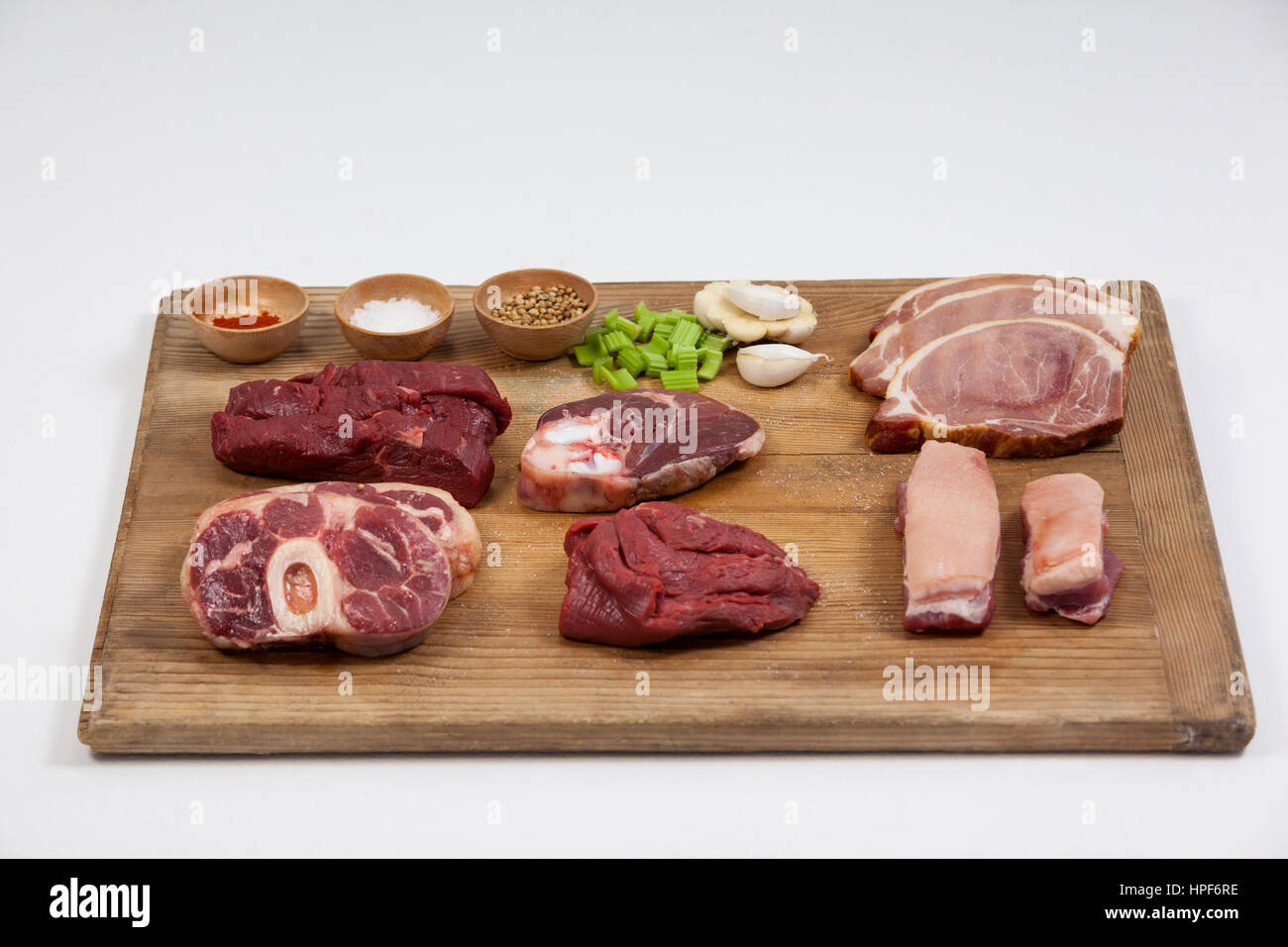 Sorten von Fleisch mit Gewürzen auf Holzbrett vor weißem Hintergrund Stockfoto