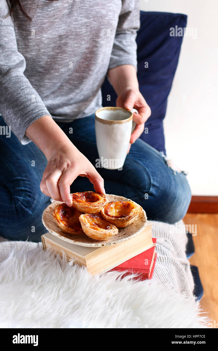 Weiblich, Frühstück im Bett. Portugiesischer Pudding Kuchen mit einer Tasse Kaffee Stockfoto