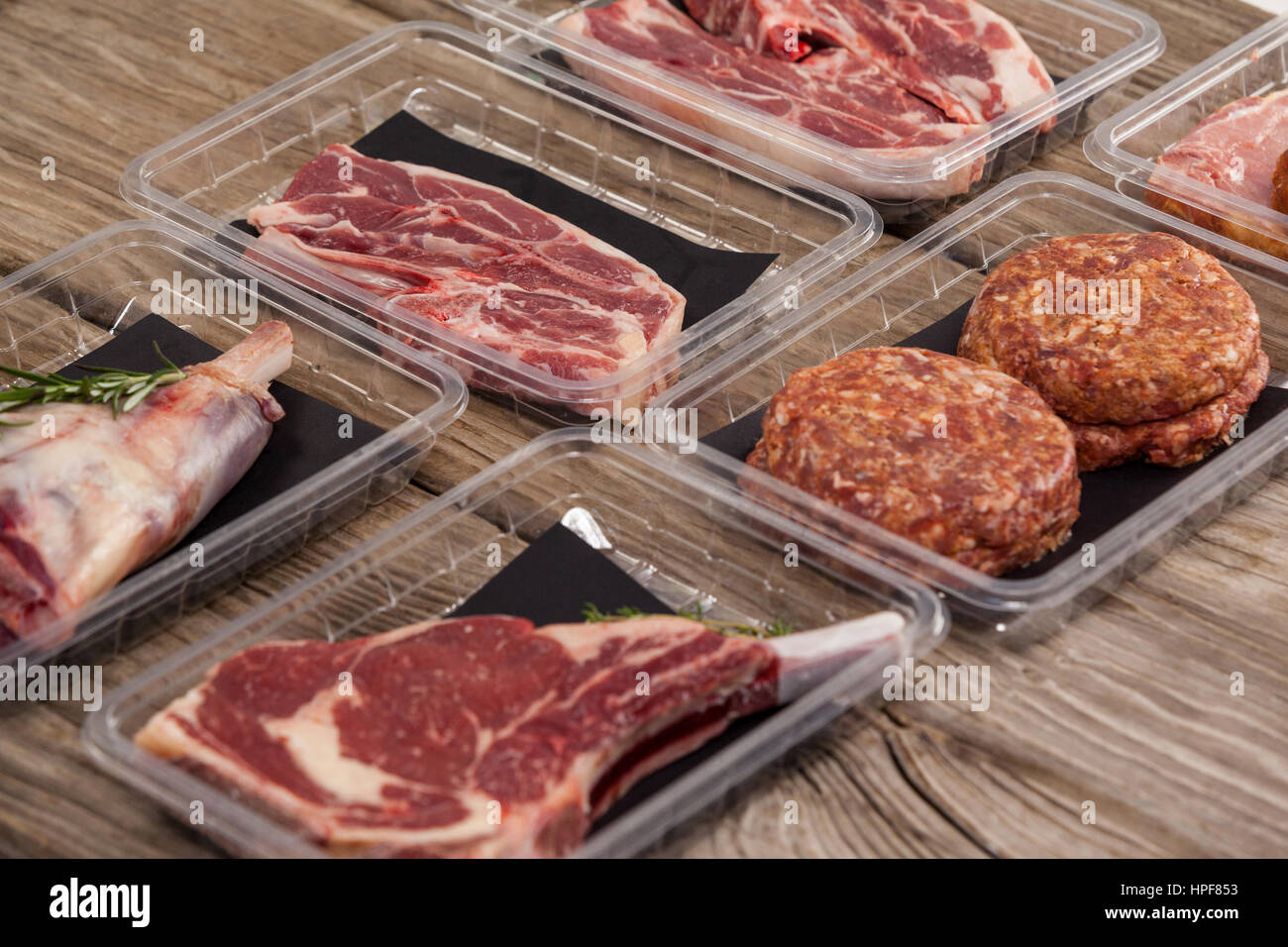 Sorten von Fleisch in Plastikboxen aus Holz Hintergrund Stockfoto