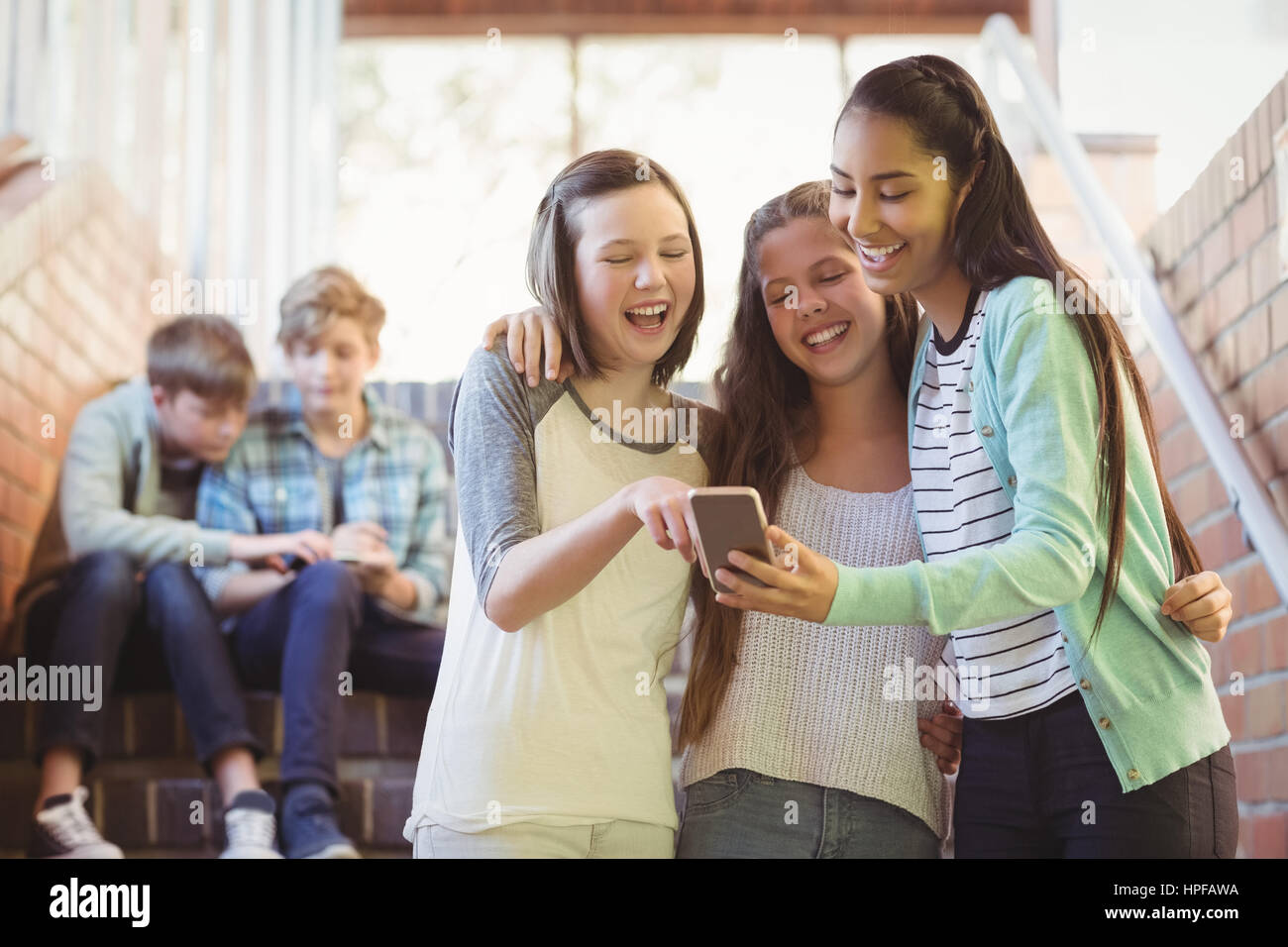 Lächelnd Schulmädchen mit Handy im Korridor in der Schule Stockfoto