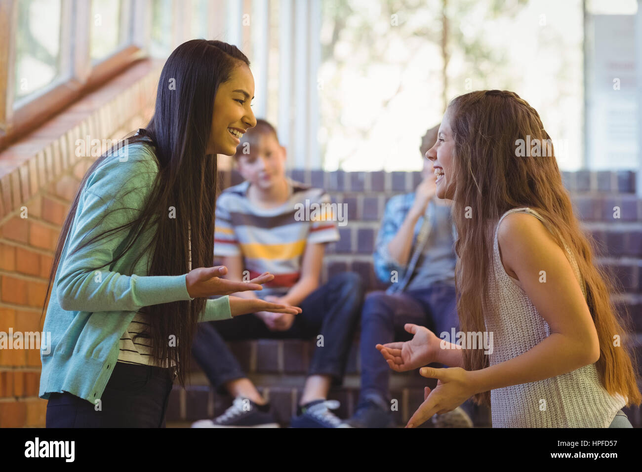 Glücklich zwei Schülerinnen, die Interaktion mit einander im Korridor in der Schule Stockfoto