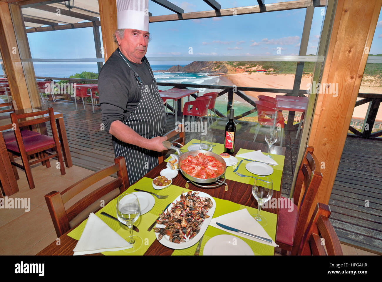 Portugal: Chef Gabriel mit seiner Spezialität des Hauses posiert auf entkernt Tisch mit Blick aufs Meer im Restaurant Gabriel II in Aljezur Stockfoto