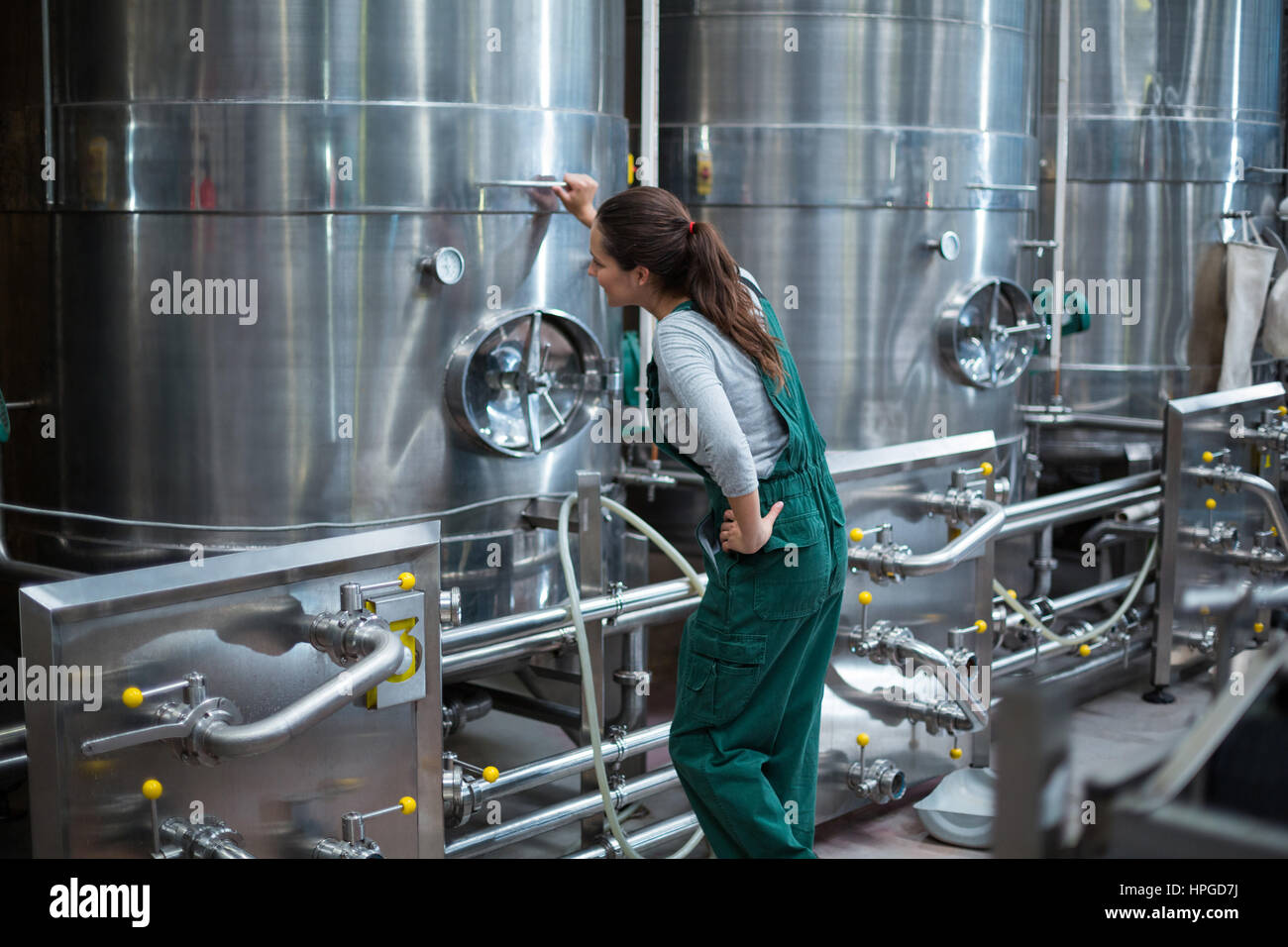 Weibliche Fabrikarbeiter Steuerrad der Lagertank Getränke Produktion Werk betrachten Stockfoto