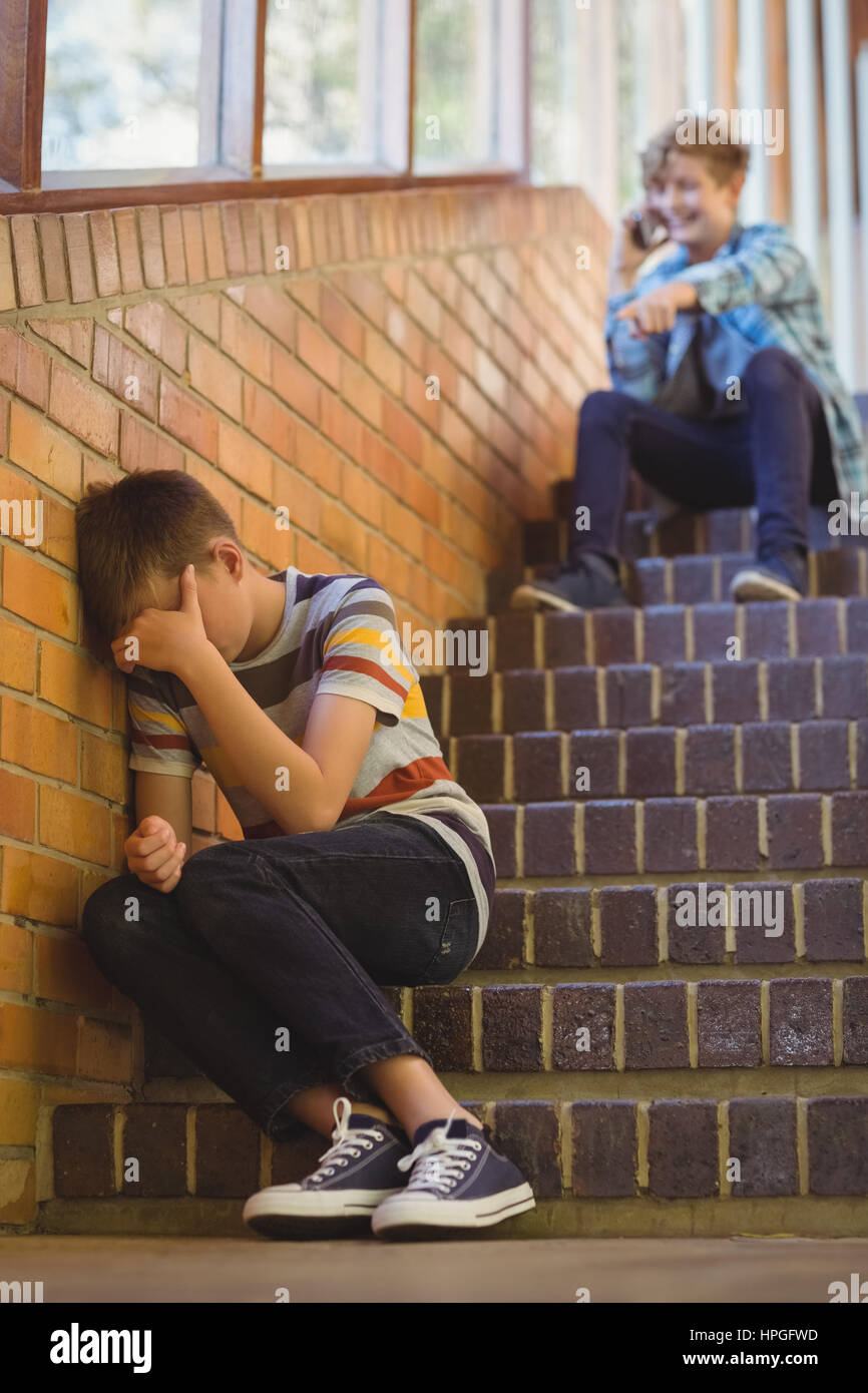 Schulfreund Mobbing einen traurigen jungen im Flur der Schule in der Schule Stockfoto