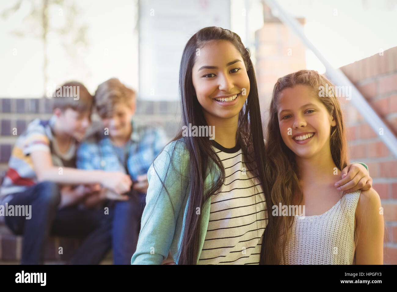Porträt des Lächelns Schulmädchen stehend mit Arm um im Korridor in der Schule Stockfoto