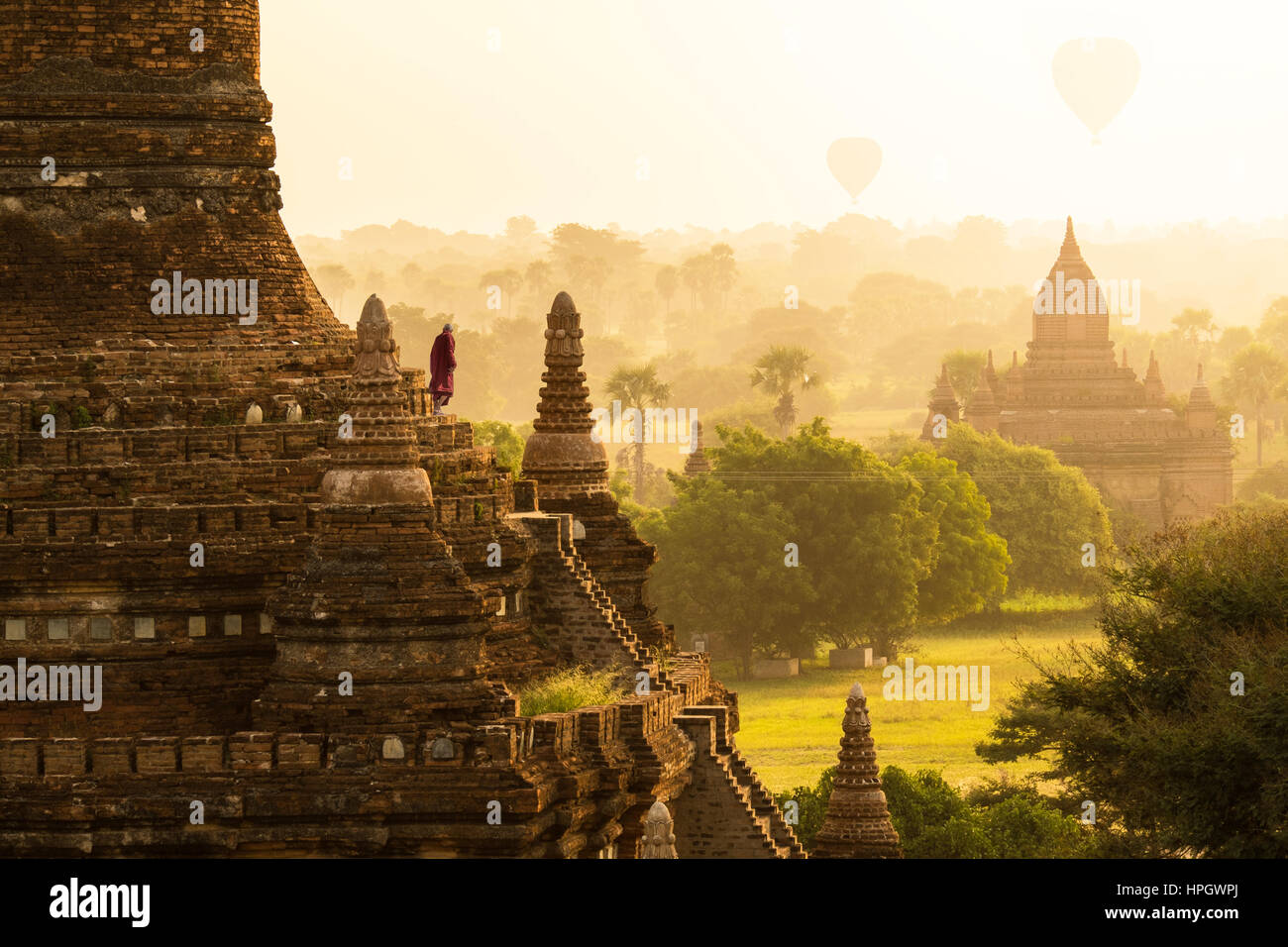 Mönch und Heißluft Ballons über Pagoden in Bagan, Myanmar Sonnenaufgang. Stockfoto