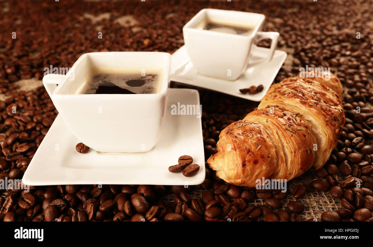 Tassen leckeren Kaffee mit Croissant und Kaffee Bohnen Stockfoto