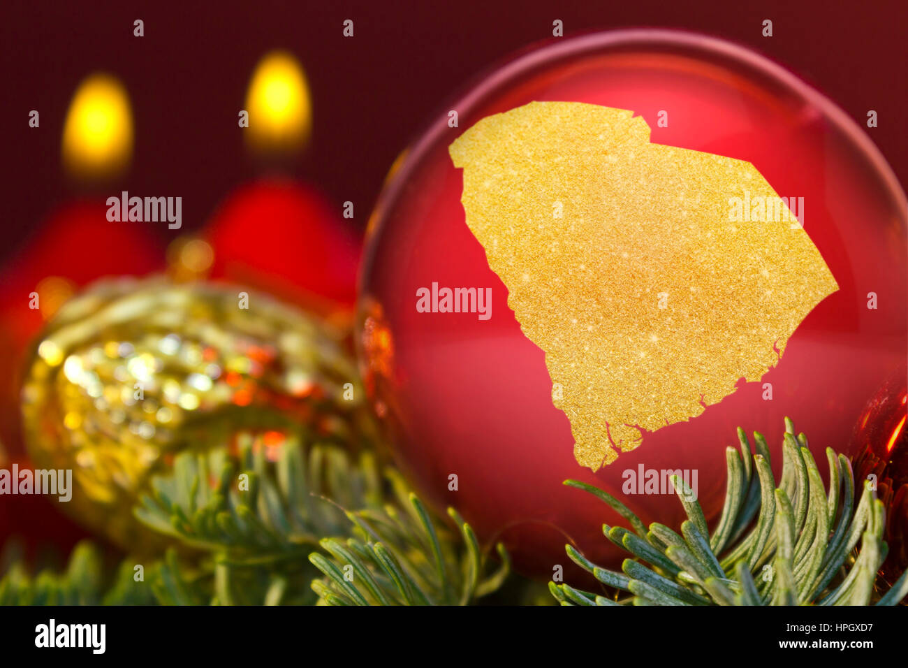 Eine glänzende rote Christbaumkugel mit der goldenen Form von South Carolina. (Serie) Stockfoto