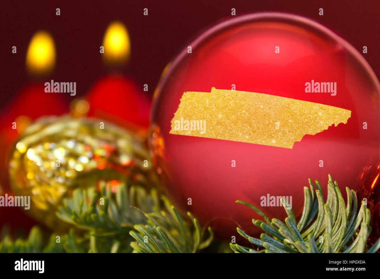 Eine glänzende rote Christbaumkugel mit der goldenen Form von Tennessee. (Serie) Stockfoto