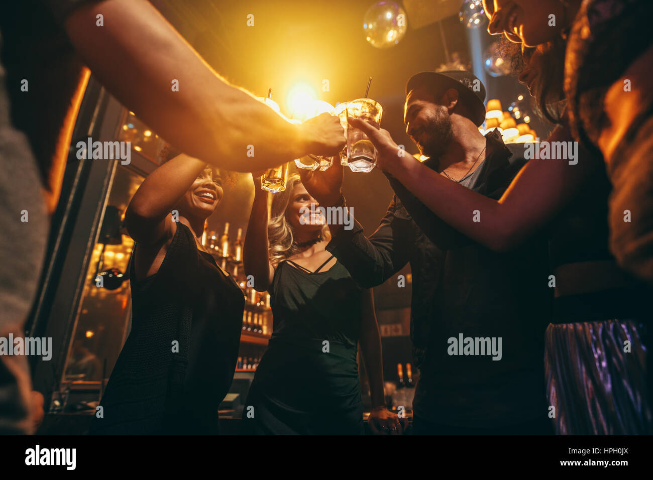 Niedrigen Winkel Schuss Gruppe von Freunden genießen Sie Drinks an der bar zusammen. Junge Menschen im Nachtclub Toasten Cocktails. Stockfoto