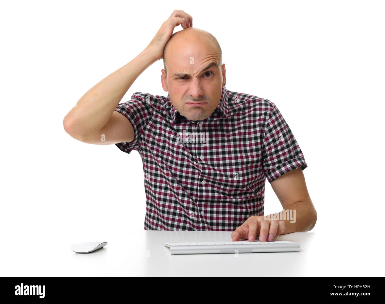 Mann sitzt an einem Schreibtisch arbeiten am Computer, kratzte sich am Kopf. Isoliert Stockfoto