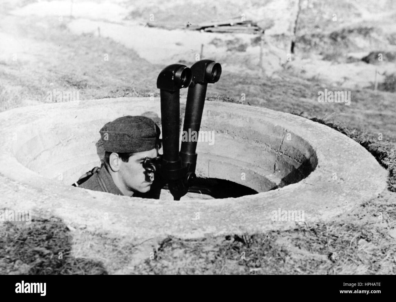 Das Bild der Nazi-Propaganda zeigt den Wächter einer deutschen Wehrmacht-Artillerie, die mit einem Doppelteleskop an der französischen Kanalküste aus dem Boden ragt. Veröffentlicht im Mai 1943. Ein Nazi-Reporter hat auf der Rückseite des Bildes geschrieben: "Feuer! Bei einer Artillerieeinheit an der Kanalküste. Der hervorstehende Aussichtspunkt befindet sich weit von der Batterie entfernt. Er ist das Auge der Artillerie. Er achtet auf die Präzision und die Wirkung der Schüsse. Seine Beobachtungen und möglichen Korrekturen werden per Telefon an die Batterie zurückgemeldet.“ Fotoarchiv für Zeitgeschichte - KEIN KABELDIENST - | weltweite Nutzung Stockfoto