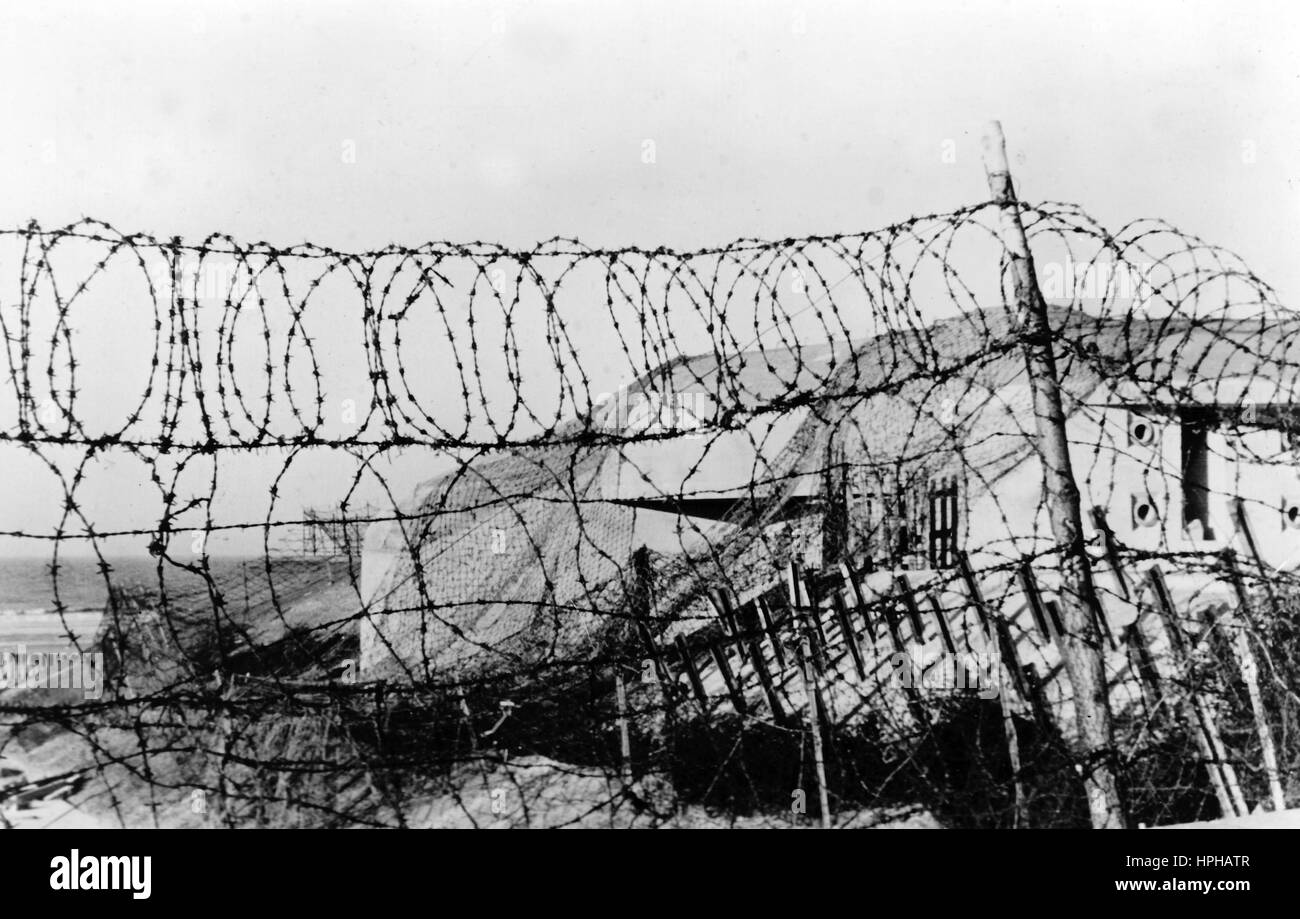 Das Bild der Nazi-Propaganda zeigt eine deutsche Wehrmachtbasis an der Atlantikmauer an der Kanalküste. Veröffentlicht im Februar 1944. Ein Nazi-Reporter schrieb auf der Rückseite des Films: "Basislager an der Kanalküste. Neben den weit flussaufwärts gelegenen Bunkern blockieren Hindernisse verschiedener Art den Weg. Betonhöcker und -Geländer, Kabelgewirr, zwischen dem die Pfosten Patrouillen halten." Fotoarchiv für Zeitgeschichte - KEIN KABELDIENST - | weltweite Nutzung Stockfoto