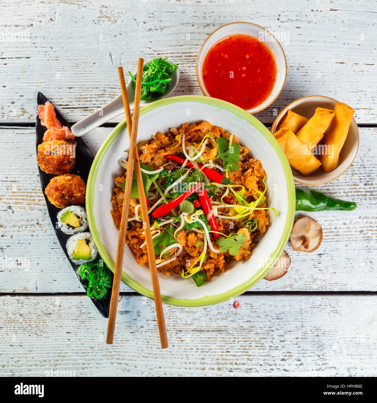 Asiatischen Huhn und Garnelen curry mit Reis und Sushi-Stücke, Ansicht von oben auf alten Holzdielen serviert. Stockfoto