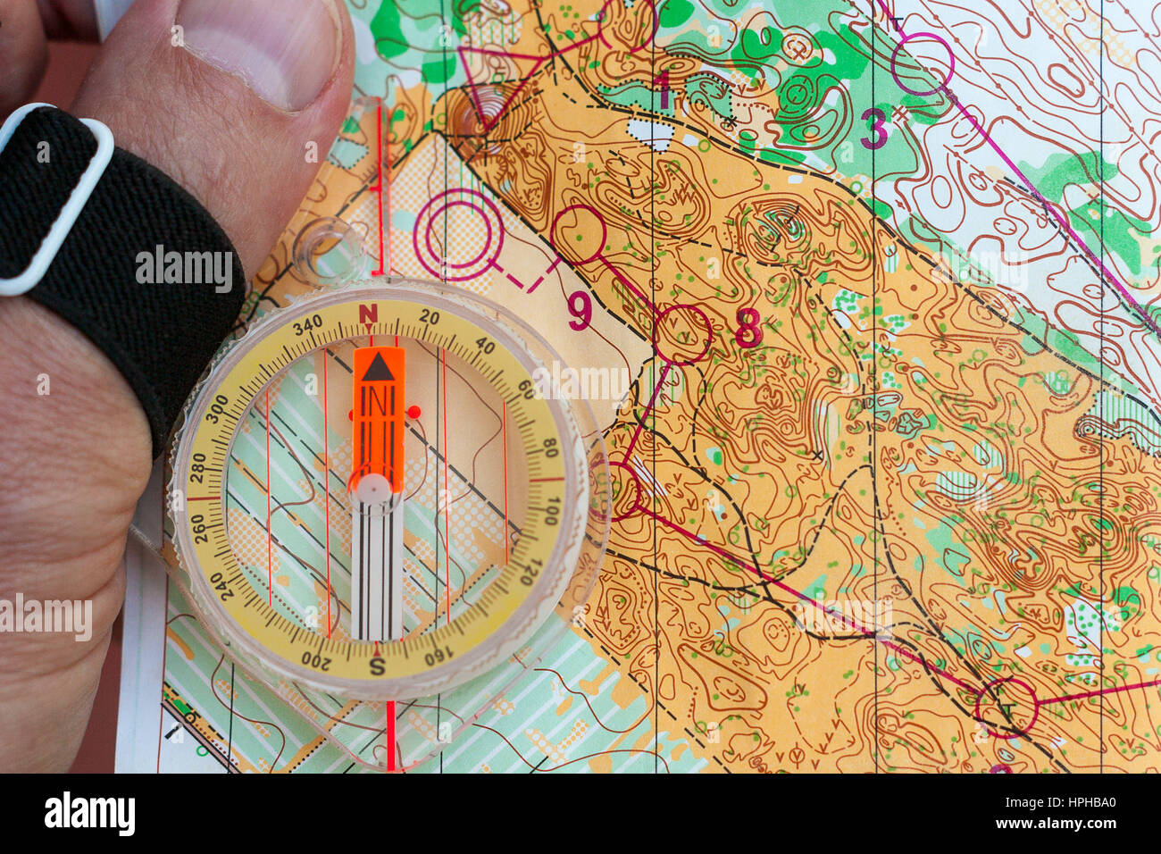 Hand hält einen Kompass auf einer OL-Karte Stockfoto