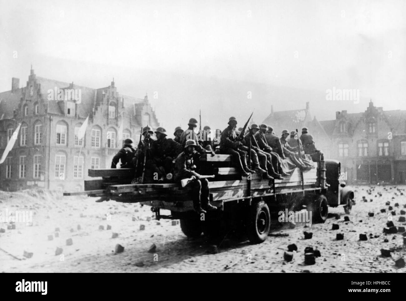 Das Bild der Nazi-Propaganda zeigt deutsche Wehrmachtingenieure, die nach der Kapitulation Belgiens in die Stadt Nieuwpoort einreisen. Veröffentlicht im Jahr 1940. Im Rathaus wurden weiße Fahnen gesetzt (l). Rechts neben dem Rathaus fehlt der zerstörte Turm der Frauenkirche (Onze-Lieve-Vrouwekerk). Ein Nazi-Reporter schrieb auf der Rückseite des Bildes auf 07.06.1940: "Deutsche Ingenieure kommen mit Baumaterial in Nieuport an, wo noch weiße Flaggen gehisst sind." Fotoarchiv für Zeitgeschichte - KEIN KABELDIENST - | weltweite Nutzung Stockfoto