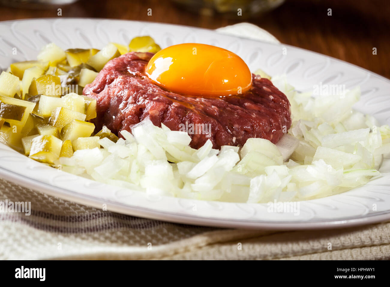 Steak Tartar mit Eigelb, Zwiebeln und Gurken auf einem Teller Stockfoto