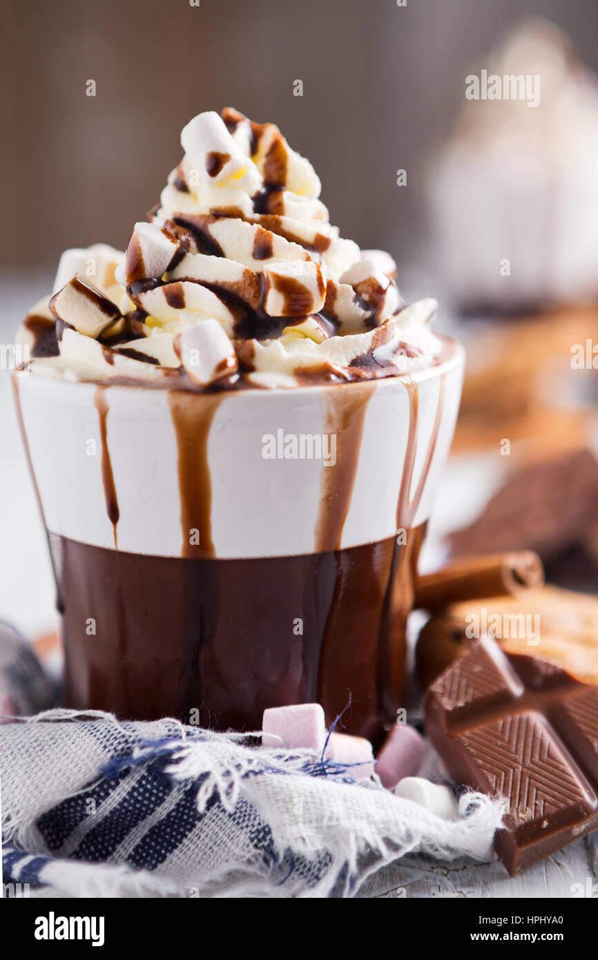 Eine unordentliche Tasse mit heißer Schokolade, Sahne, Marshmallows und Schokoladenkekse. Stockfoto