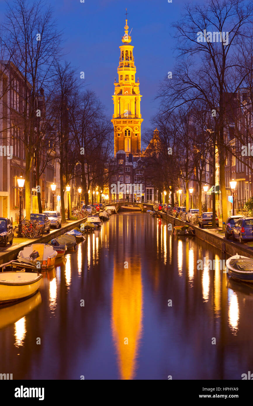 Ein Kirchturm am Ende eines Kanals in der Stadt Amsterdam, die Niederlande in der Nacht. Stockfoto