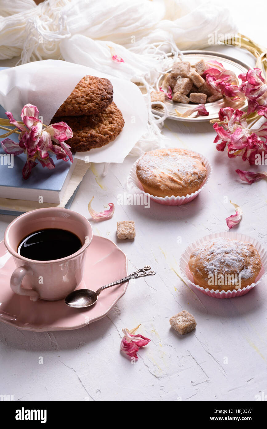 Frühstück - Hafer-Kekse, Vanille Muffins mit Zuckerguss, schwarzen Kaffee. Nahaufnahme, weißen Tisch, Licht des Morgens Stockfoto