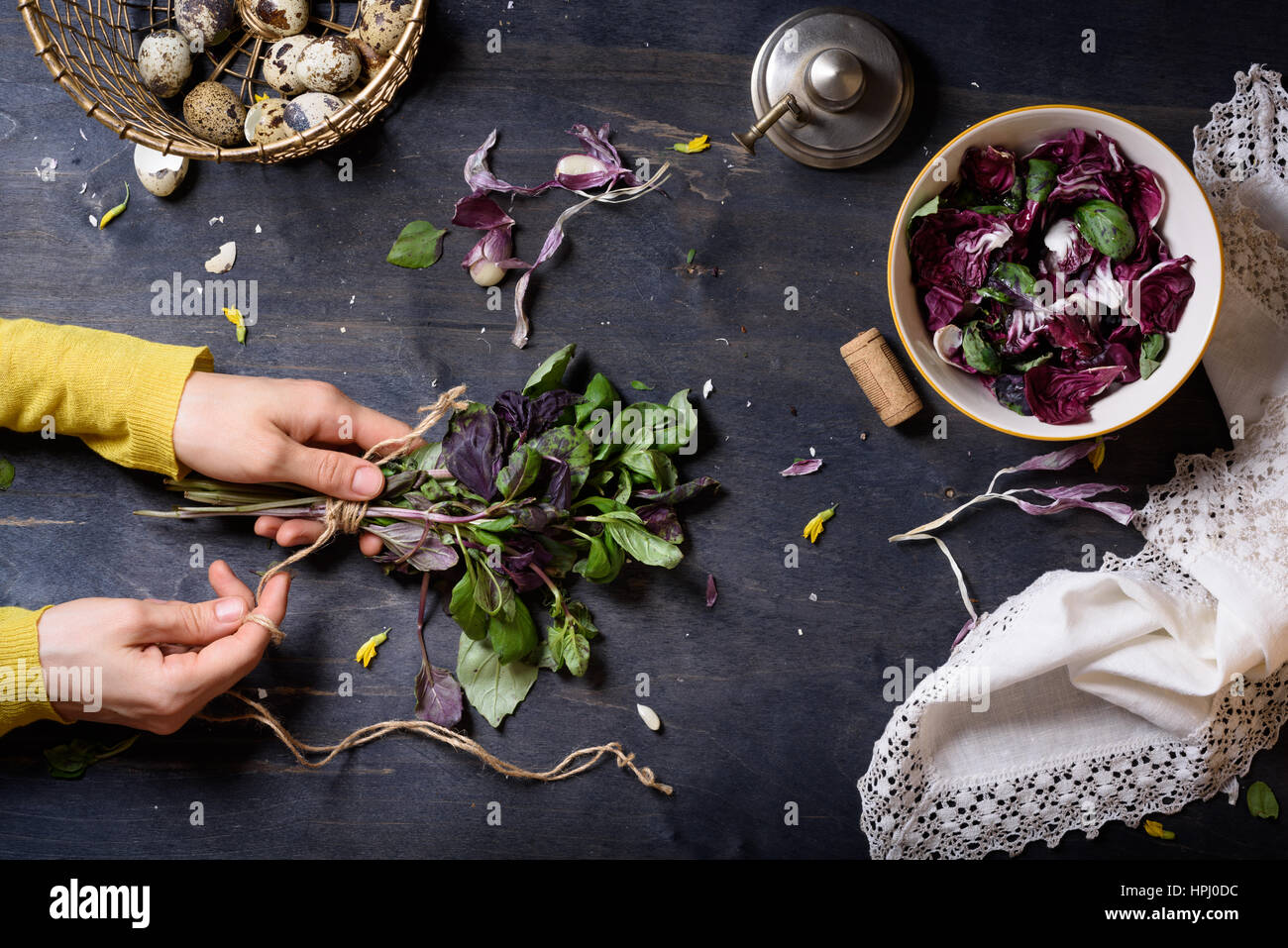 Frau Hände Kochen Salat mit frischem Basilikum, Radicchio Blätter und Eiern. Holztisch, direkt von oben. Stockfoto