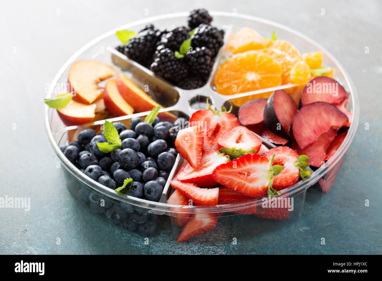 Verschiedene Früchte und Beeren auf einem Teller mit Erdbeeren, Pfirsiche, Brombeeren und orange Stockfoto