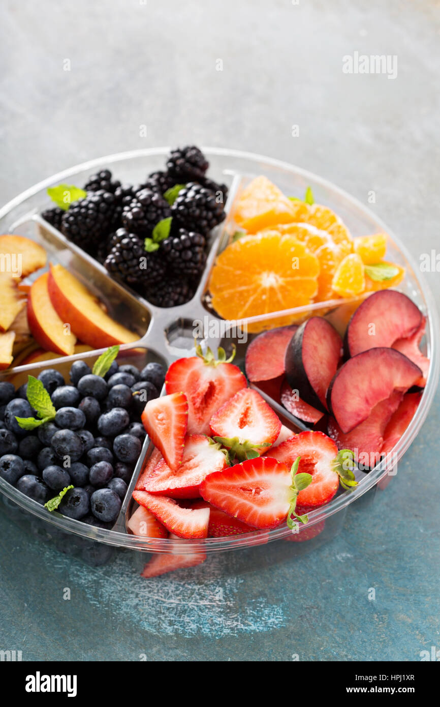 Verschiedene Früchte und Beeren auf einem Teller mit Erdbeeren, Pfirsiche, Brombeeren und orange Stockfoto