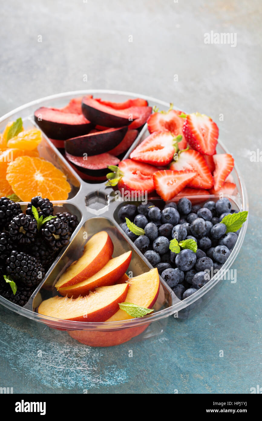Verschiedene Früchte und Beeren auf einem Teller mit Erdbeeren, Pfirsiche, Brombeeren und orange Stockfoto