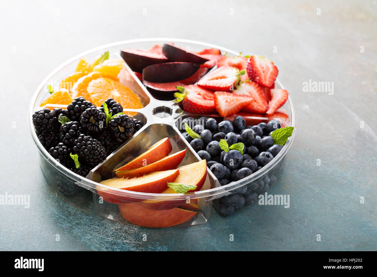 Verschiedene Früchte und Beeren auf einem Teller mit Erdbeeren, Pfirsiche, Brombeeren und orange Stockfoto