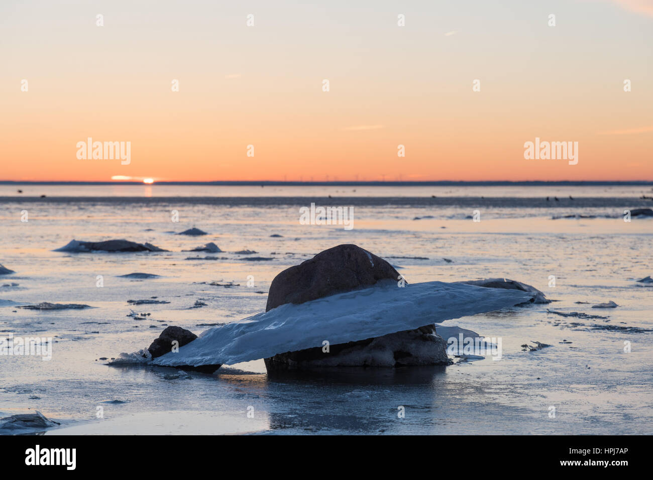 Eisbildung an einem Felsen am Strand bei Sonnenuntergang Stockfoto