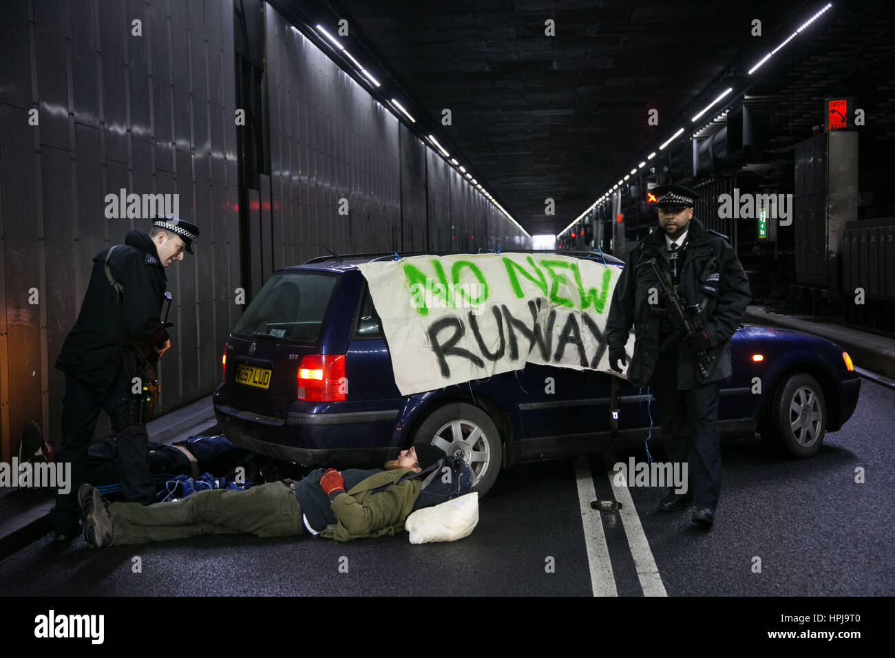 Polizei an drei Klima-Aktivisten, die die eingehenden Tunnel an den Flughafen Heathrow in blockiert haben protestieren gegen eine neue dritte Start-und Landebahn. Stockfoto