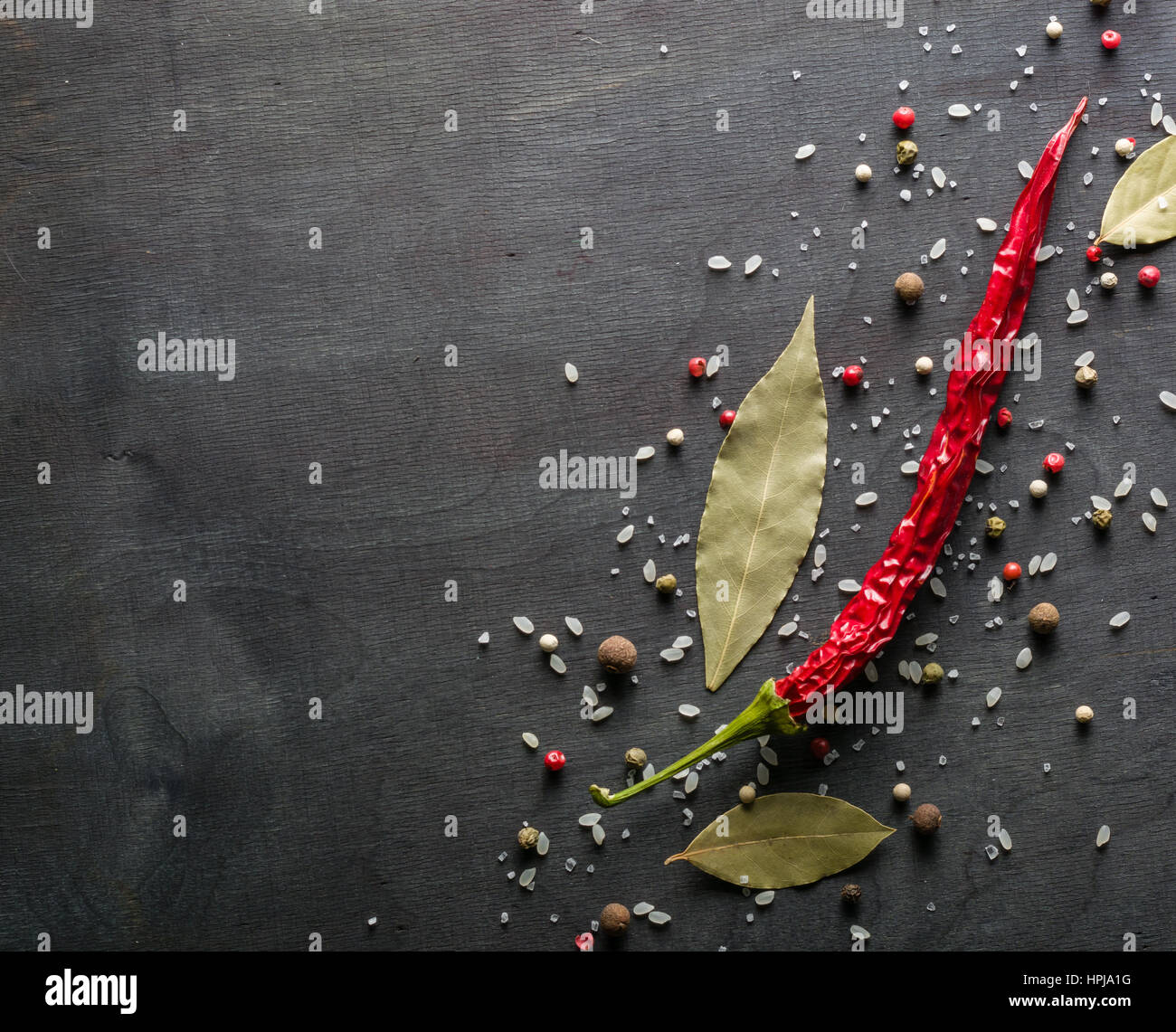 Rote Paprika, scharfe Gewürze und Lorbeerblatt auf dem schwarzen Baum. Ansicht von oben. Platz für Text. Stockfoto