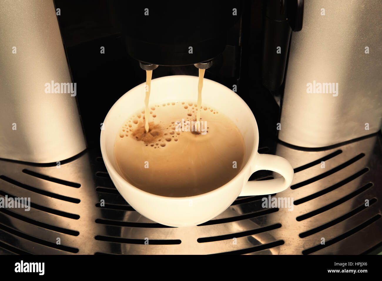Gießen von Kaffeemaschine in eine weiße Tasse Kaffee Stockfoto