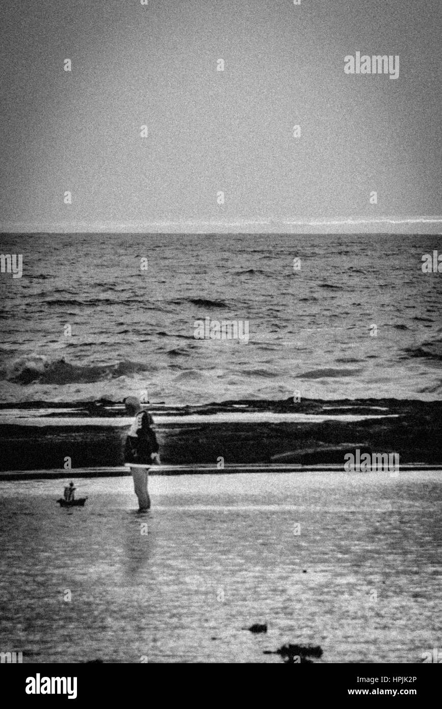 Alter Mann spielt mit remote Boot am Strand bei Sonnenaufgang Stockfoto