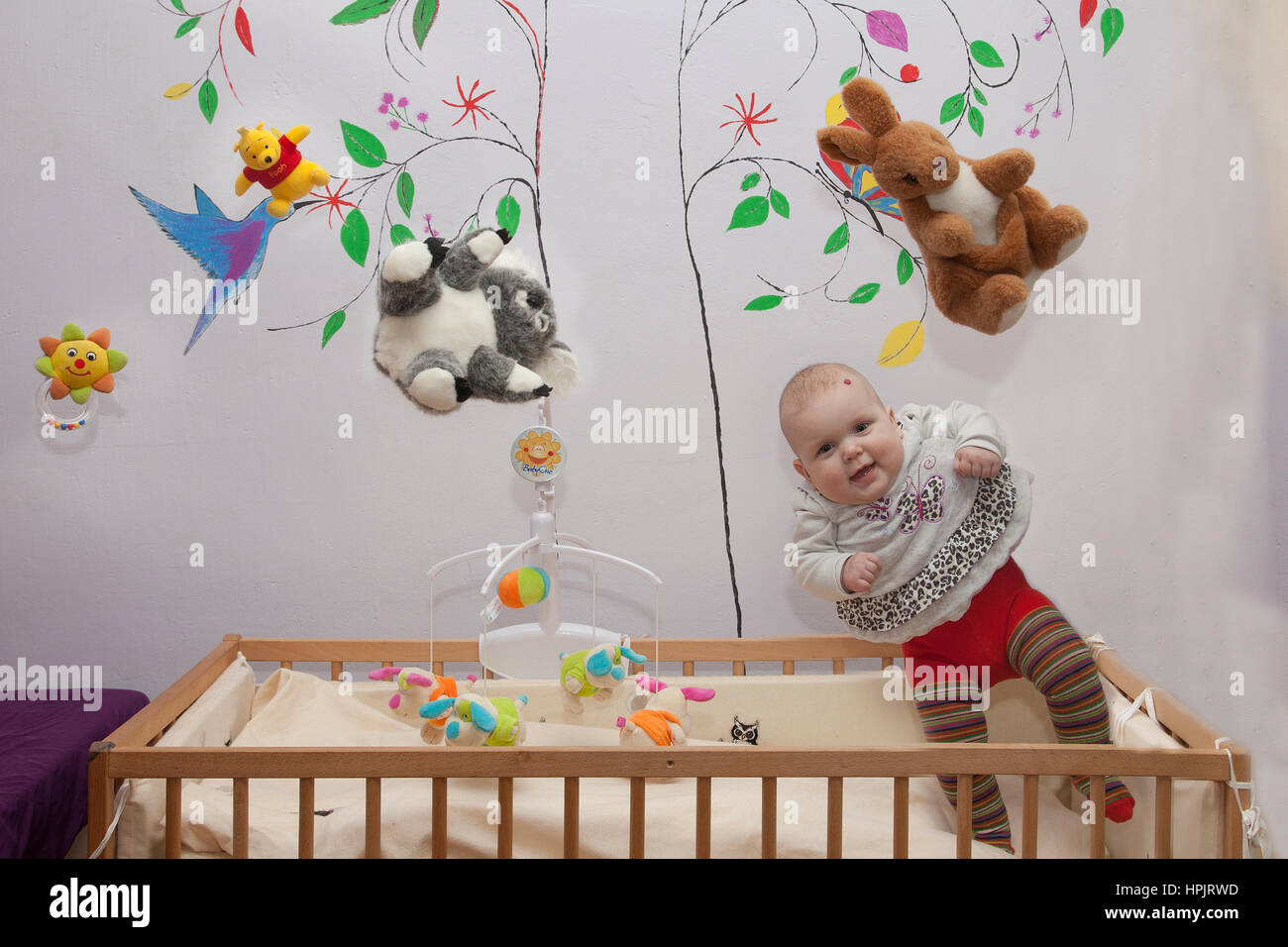 Baby Mädchen sitzen fliegen auf dem Bett auf weißem Hintergrund Stockfoto