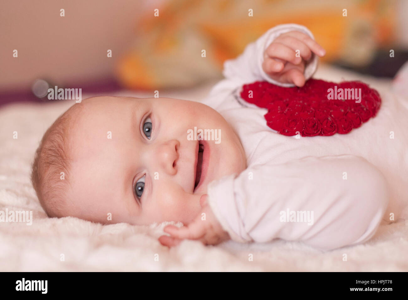 Baby Mädchen sitzen fliegen auf dem Bett auf weißem Hintergrund Stockfoto