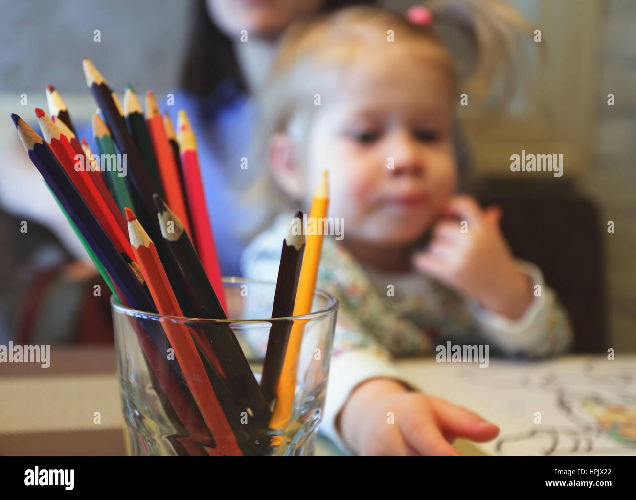 bunte Bleistifte in Glas mit Kind und Mutter auf Hintergrund Stockfoto