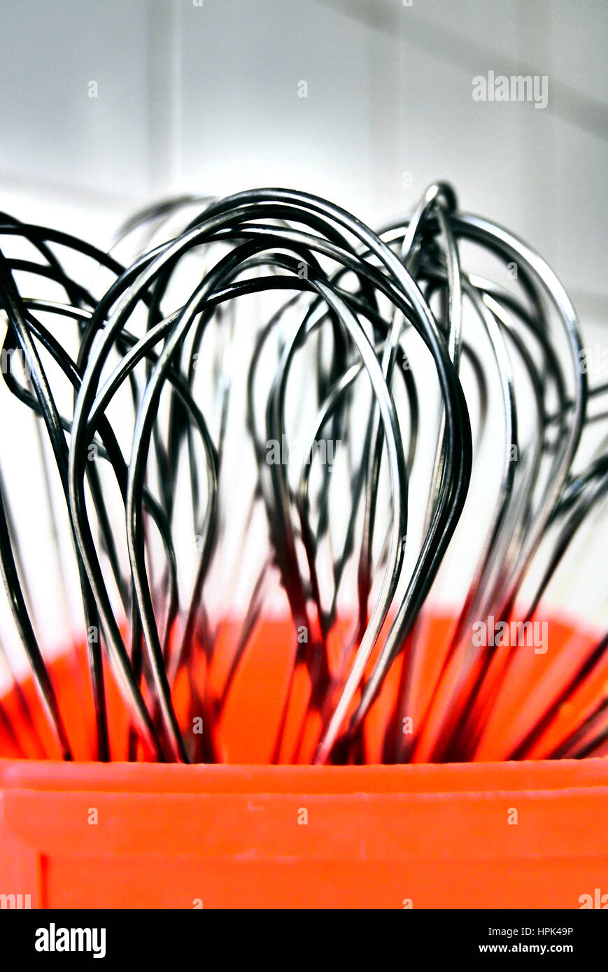 Metall Essen Rührbesen in roten Kunststoff-Container Hintergrund weiß geflieste Küche Stockfoto
