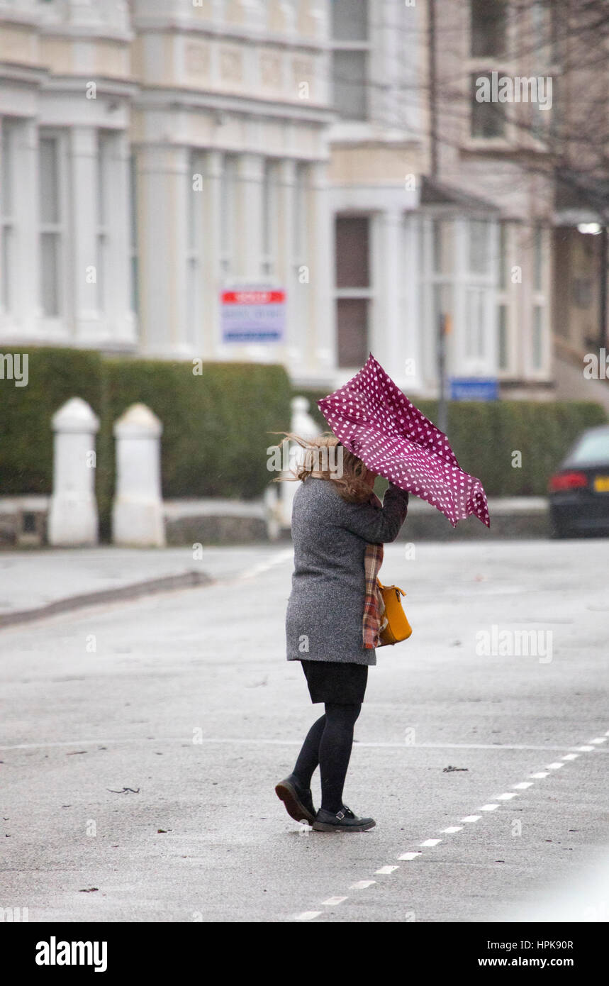 Weibliche Pendler zu Fuß zur Arbeit bei nassen und windigen Wetter infolge Sturm Doris, da traf es Llandudno, Nordwales Stockfoto