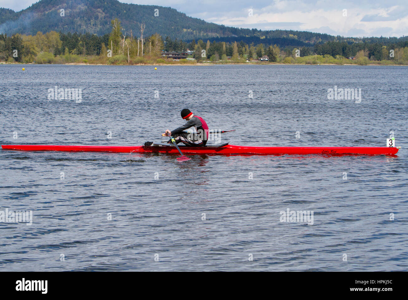 Ein Teenager Ruderer Sportler, an einem Fluss in einem Einzel-Ruderboot Stockfoto