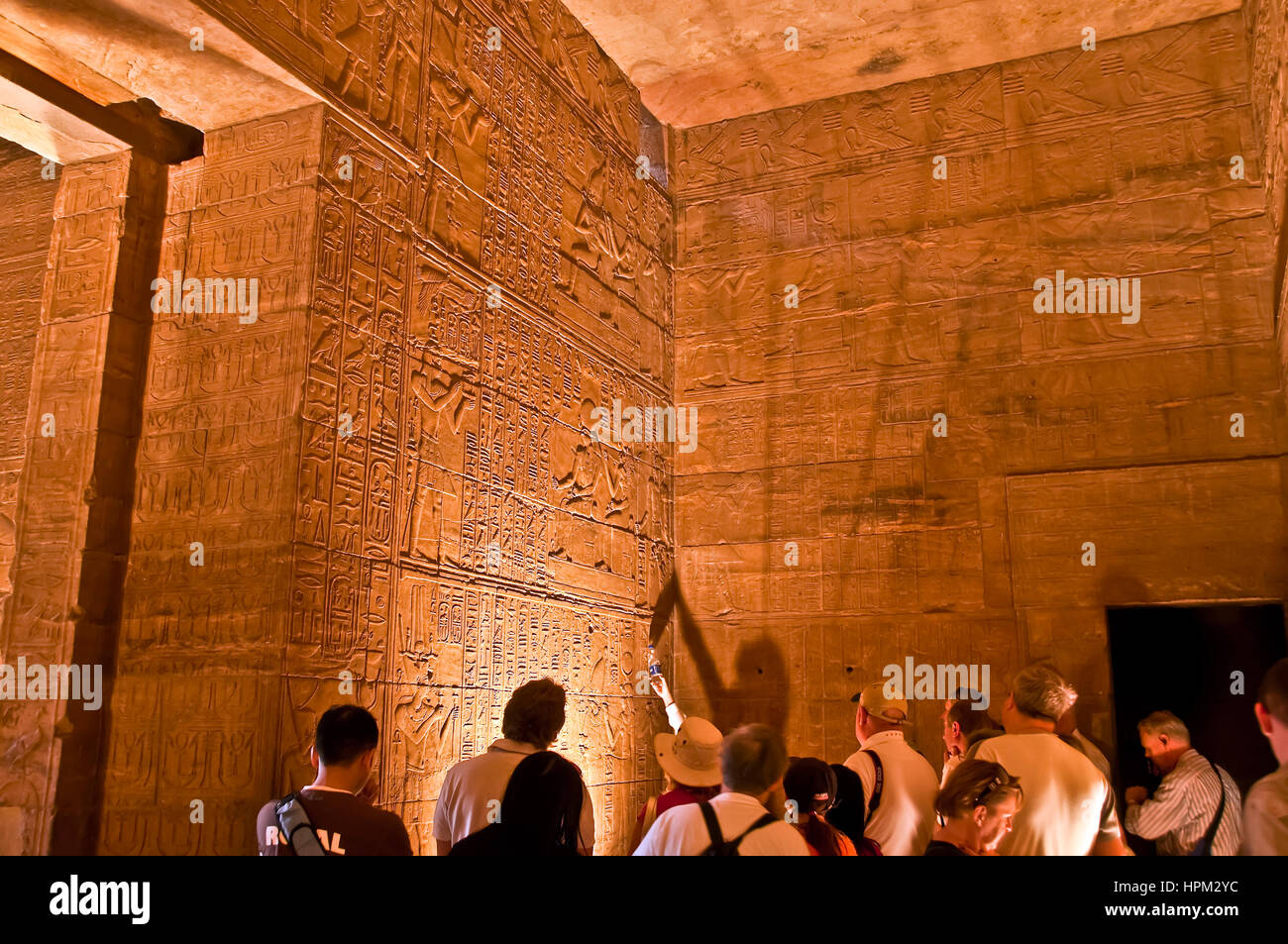 Gruppe von Touristen mit Guide in Philae Tempel Führungspunkte an Wand bedeckt mit Hieroglyphen Stockfoto