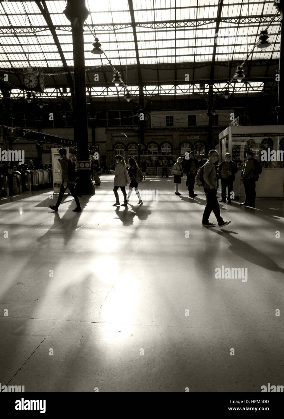 schwarz / weiß Foto von Pendlern in Zug Bahnhof Wlaking auf Plattformen, ist Sonne kommen durch ein Glasdach und erfüllten die Pendler-Form Stockfoto